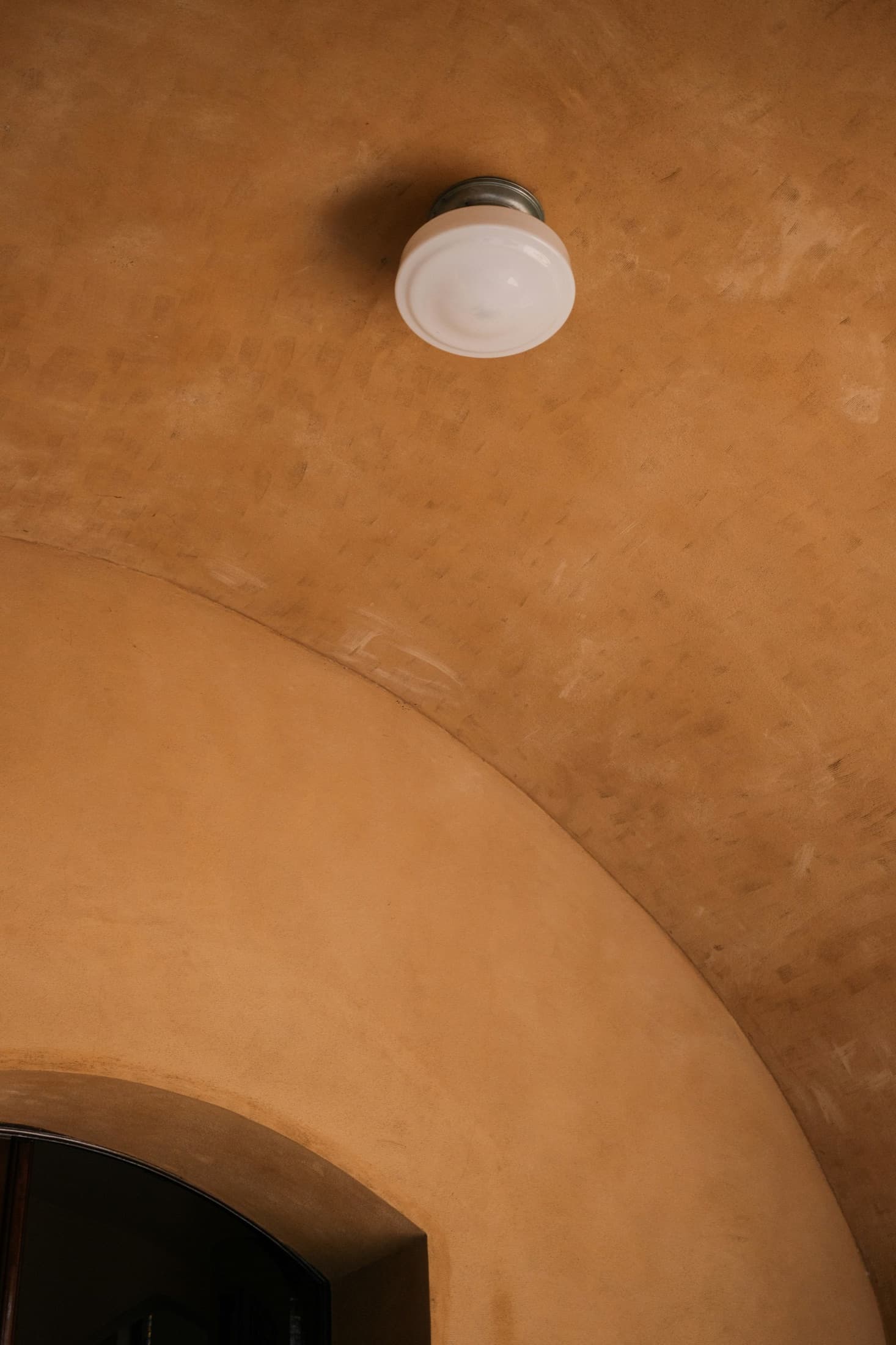 Arco de paredes lisas en tono terracota con luz cálida